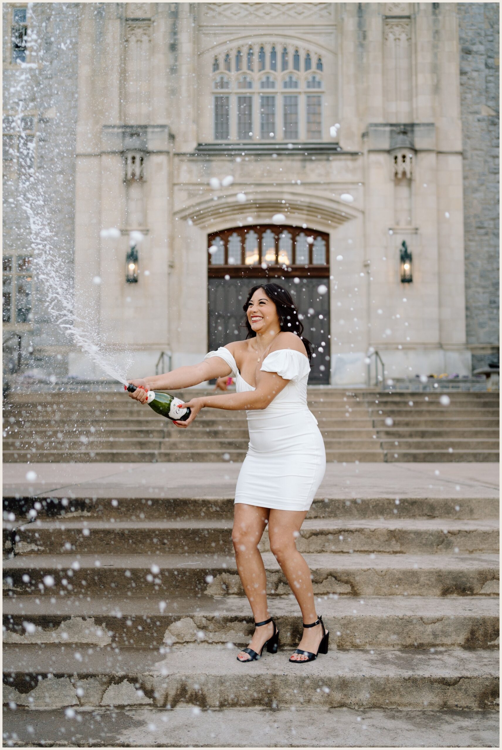 Virginia Tech graduation portrait of a woman popping champagne