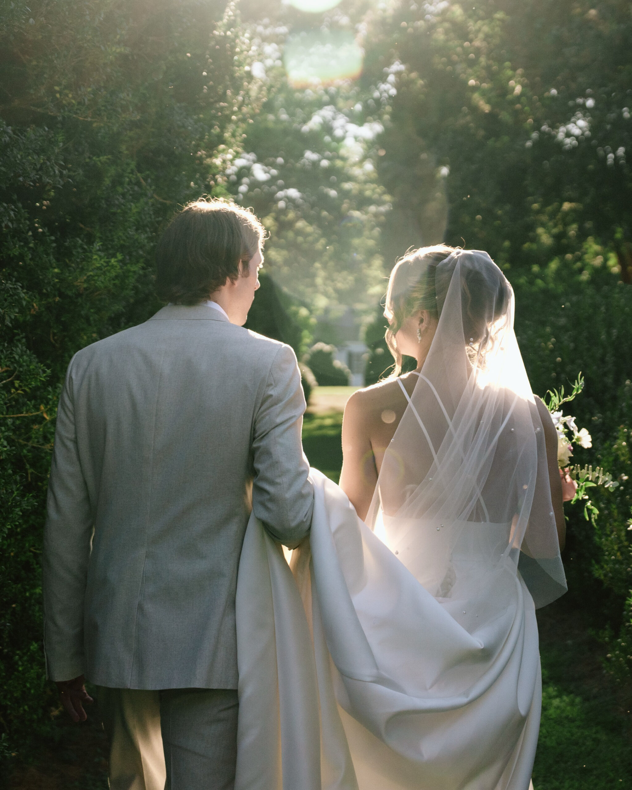 bride and groom walking through garden